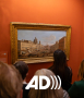 Osoby oglądające obraz na wystawie "Włoskie widoki van Wittela" z logiem audiodeksrypcji