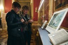 Goście oglądający dary wyeksponowane w gablotach w Sali Rady